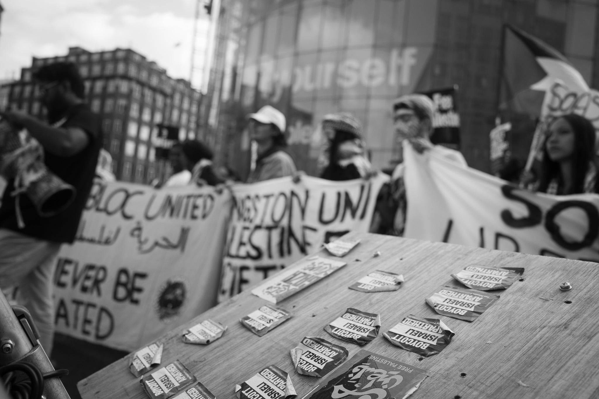 Torn stickers on a wooden surface, blurred banners and marchers in the background