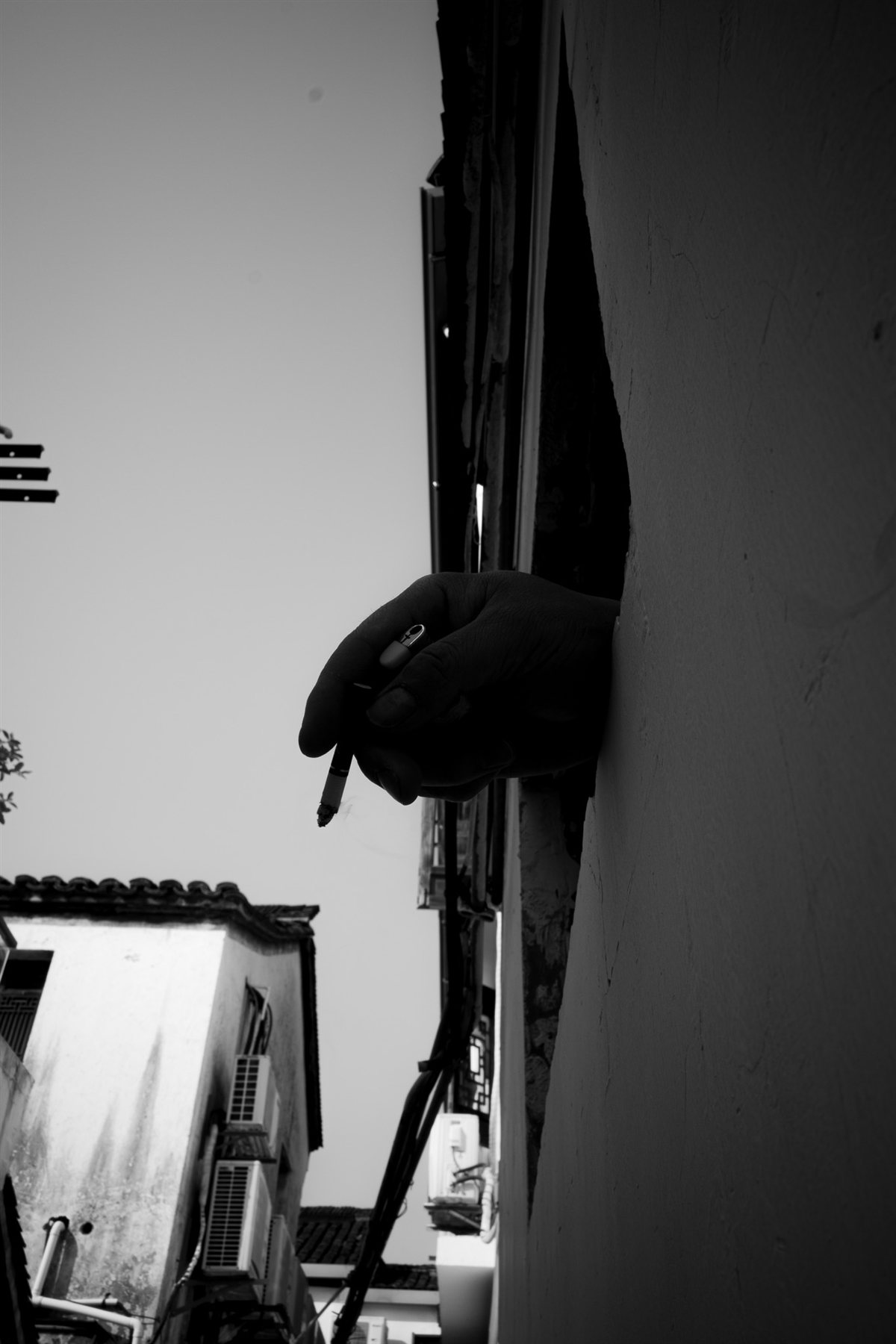 A hand holding a cigarette out of a window