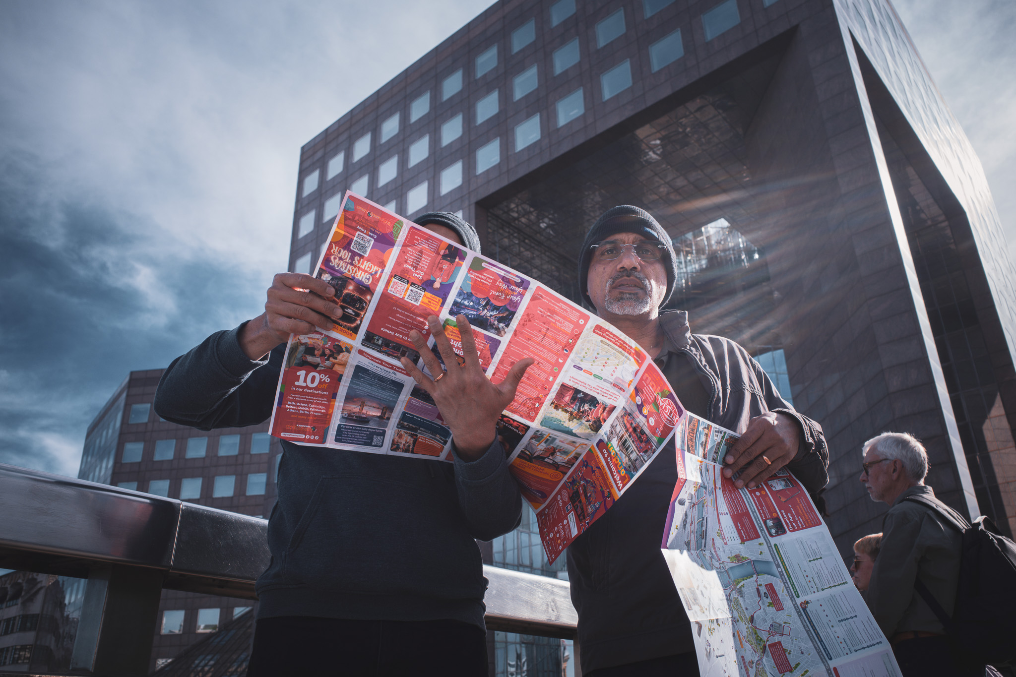 Two tourists holding a sightseeing leaflet open in front of their faces